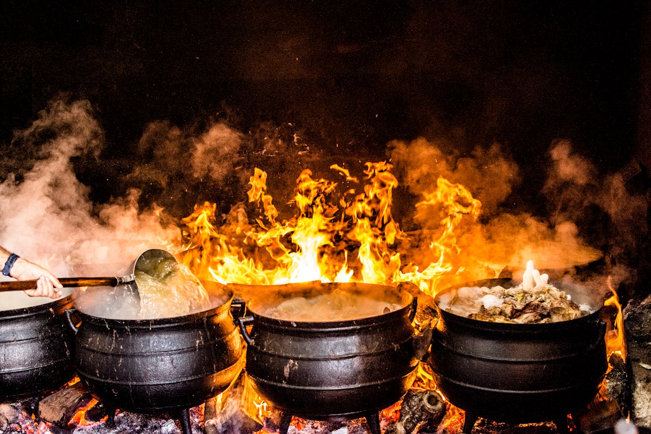 Vibrant outdoor cooking scene with large pots over open flame, showcasing traditional Açores methods.